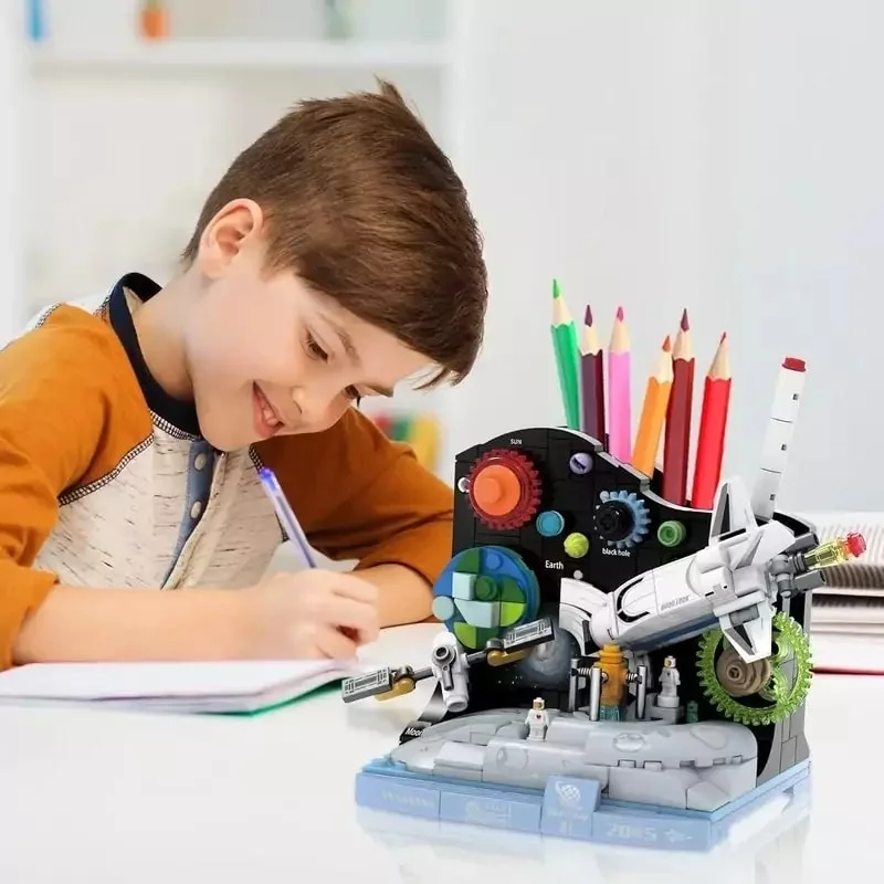 کودک در حال استفاده از لگو جامدادی کیهان کاوشگر فضا به عنوان جامدادی و نوشتن در دفتر تحریر